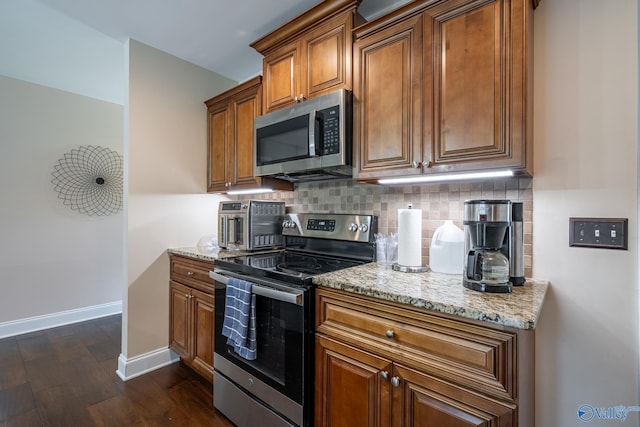 915 County Road 349, Leesburg, AL 35983 - kitchen with tasteful backsplash, light stone counters, brown cabinetry, baseboards, and appliances with stainless steel finishes