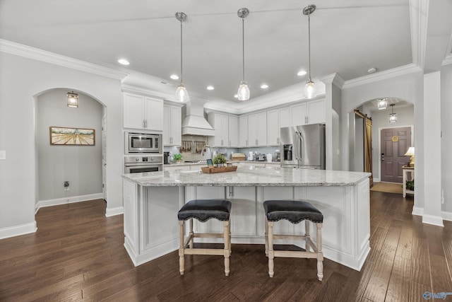 7417 Nature Walk Way SE, Owens Cross Roads, AL 35763 - kitchen featuring appliances with stainless steel finishes, arched walkways, custom exhaust hood, a barn door, and ornamental molding