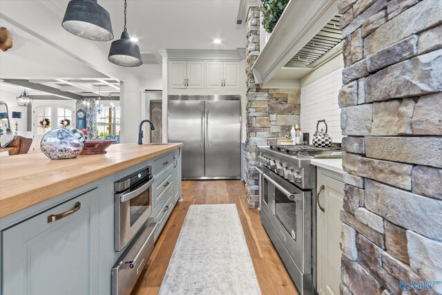 kitchen featuring premium appliances, wooden counters, decorative light fixtures, gray cabinets, and custom exhaust hood