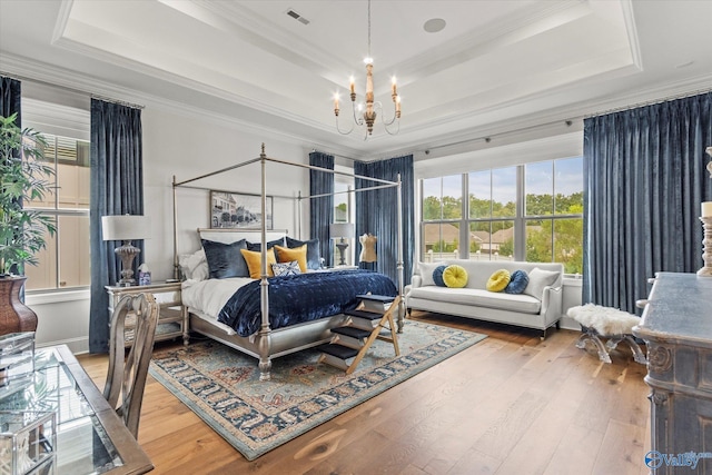 bedroom with a raised ceiling, wood-type flooring, a notable chandelier, and ornamental molding