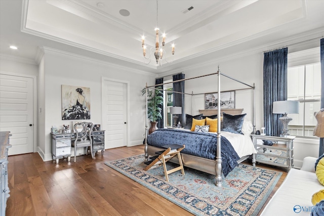 bedroom featuring dark hardwood / wood-style flooring, a raised ceiling, ornamental molding, and an inviting chandelier