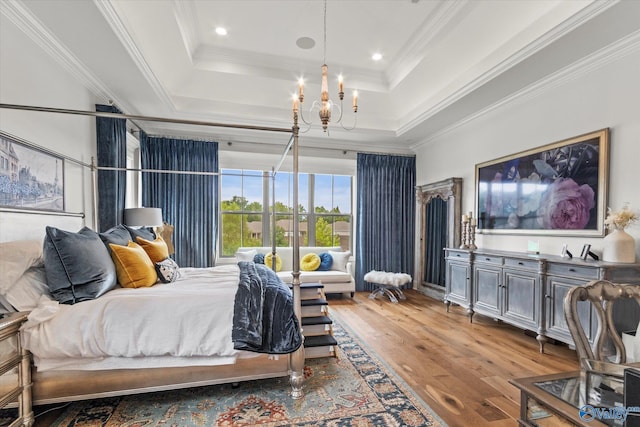 bedroom featuring hardwood / wood-style flooring, a notable chandelier, a raised ceiling, and crown molding