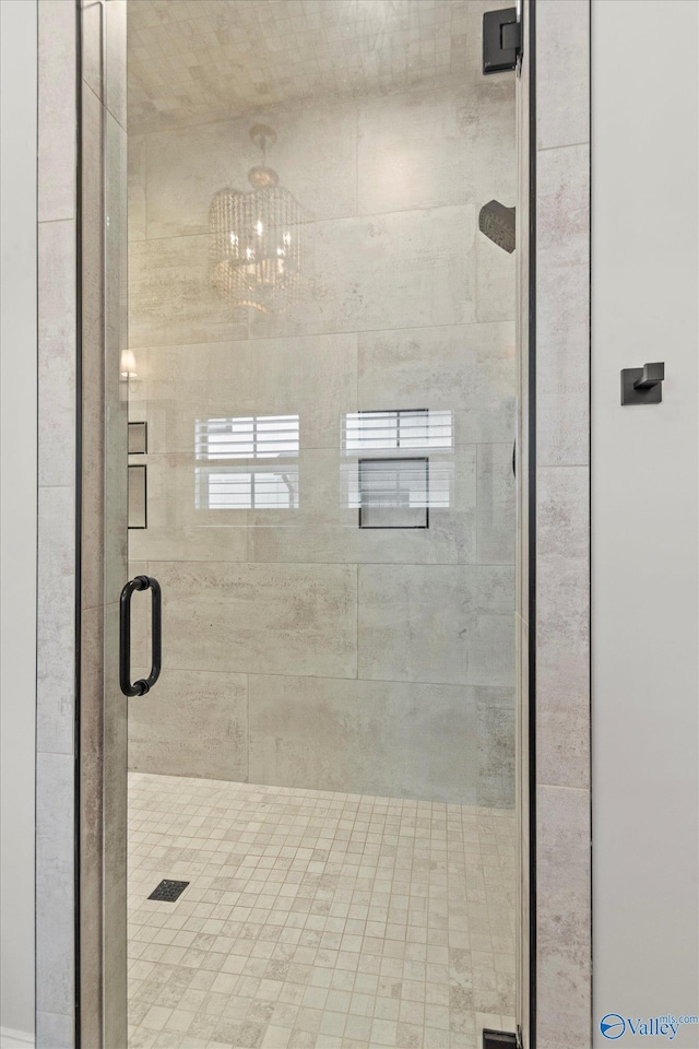 bathroom featuring a shower with door and a chandelier