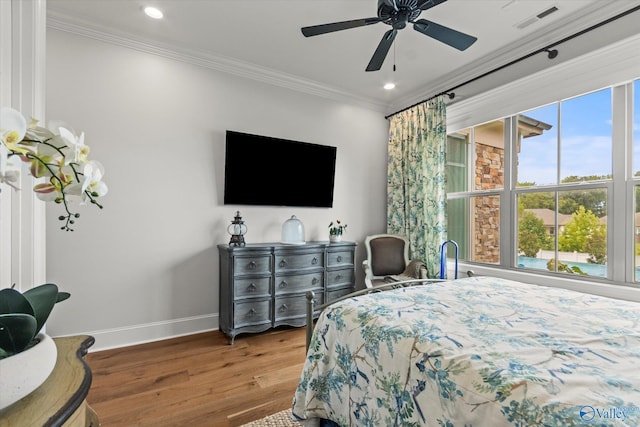 bedroom featuring ceiling fan, wood-type flooring, crown molding, and multiple windows