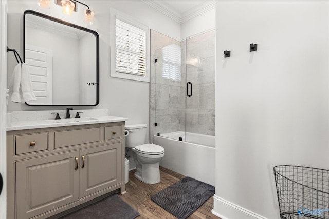 full bathroom featuring hardwood / wood-style floors, vanity, bath / shower combo with glass door, crown molding, and toilet