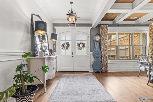 foyer with french doors, ornamental molding, coffered ceiling, a healthy amount of sunlight, and beamed ceiling