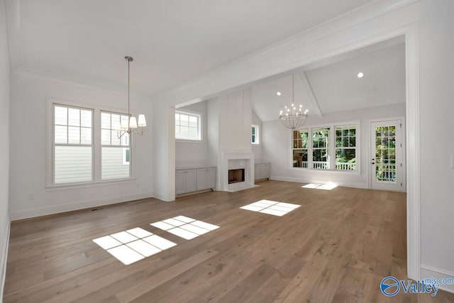 unfurnished living room featuring lofted ceiling, a wealth of natural light, a chandelier, and light wood-type flooring