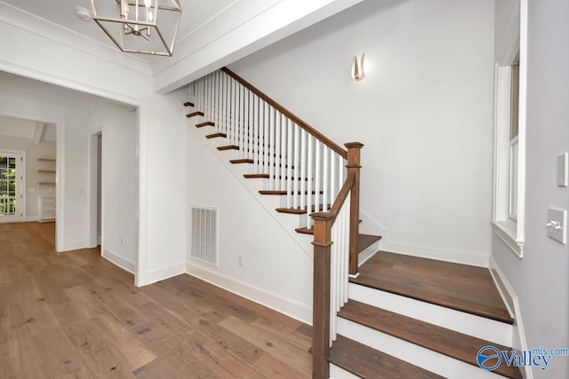 stairway featuring hardwood / wood-style floors and a chandelier