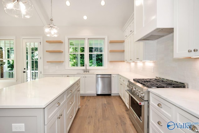 kitchen featuring premium range hood, decorative light fixtures, white cabinetry, sink, and stainless steel appliances