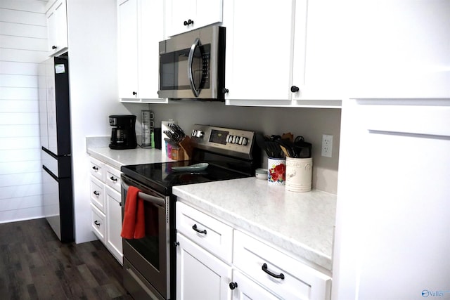 kitchen with appliances with stainless steel finishes, dark hardwood / wood-style flooring, and white cabinets