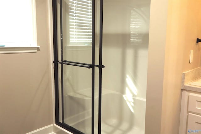 bathroom with vanity, a shower with door, and a healthy amount of sunlight