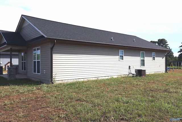 view of side of property featuring central AC and a lawn