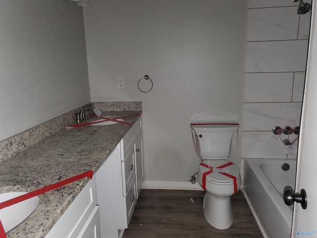 bathroom with hardwood / wood-style floors, vanity, a tub to relax in, and toilet