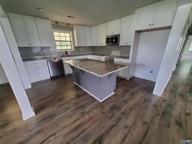 kitchen featuring dark hardwood / wood-style flooring, a center island, white cabinets, and stainless steel appliances