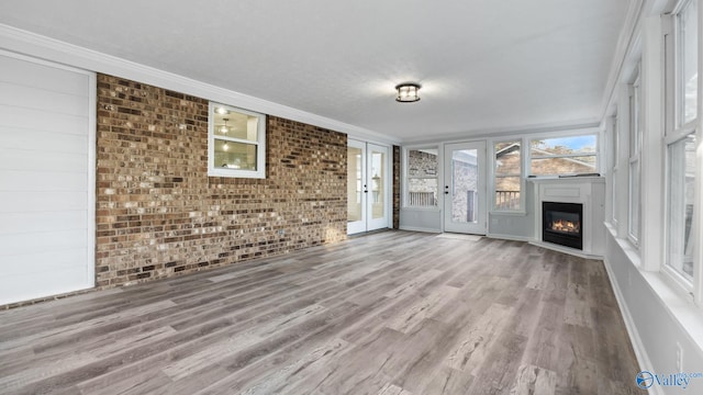 2055 Big Nose Dr, Centre, AL 35960 - unfurnished living room featuring brick wall, wood finished floors, a glass covered fireplace, ornamental molding, and baseboards