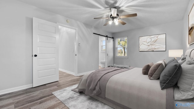 2055 Big Nose Dr, Centre, AL 35960 - bedroom featuring a barn door, wood finished floors, baseboards, connected bathroom, and a ceiling fan