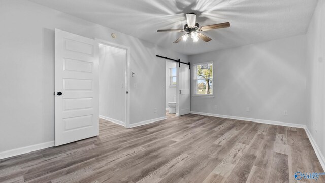 2055 Big Nose Dr, Centre, AL 35960 - unfurnished bedroom featuring wood finished floors, baseboards, a barn door, and ensuite bath