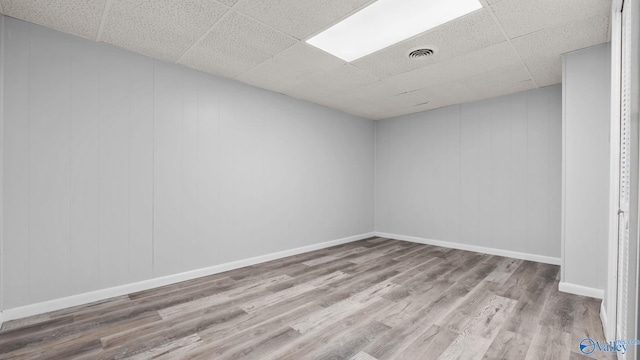 spare room with light hardwood / wood-style flooring and a drop ceiling