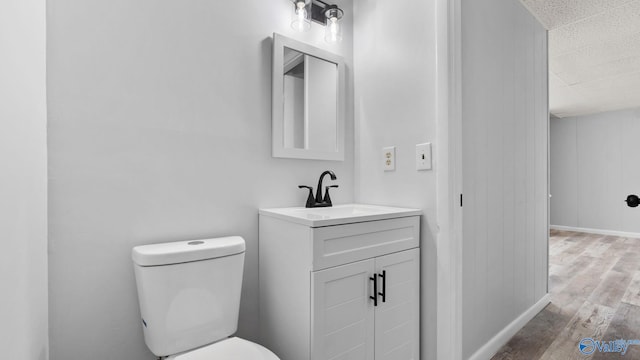 bathroom with hardwood / wood-style floors, vanity, and toilet