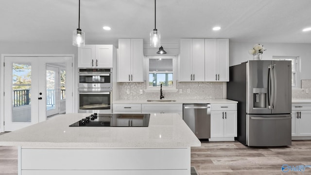 kitchen featuring stainless steel appliances, white cabinetry, a healthy amount of sunlight, and light stone counters