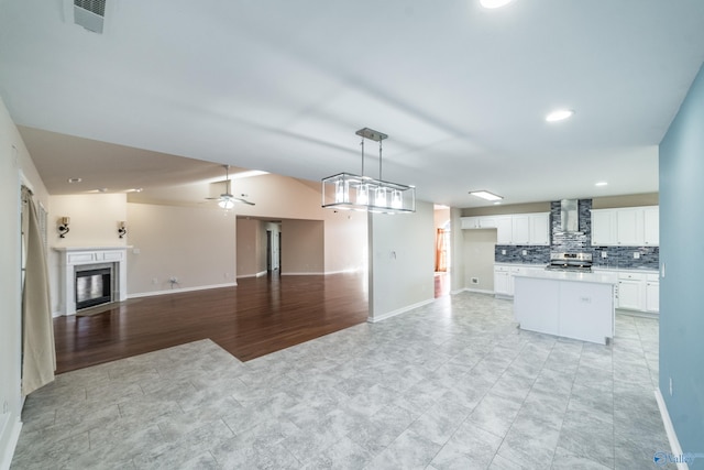 kitchen featuring stainless steel electric range, white cabinets, light hardwood / wood-style flooring, wall chimney exhaust hood, and ceiling fan