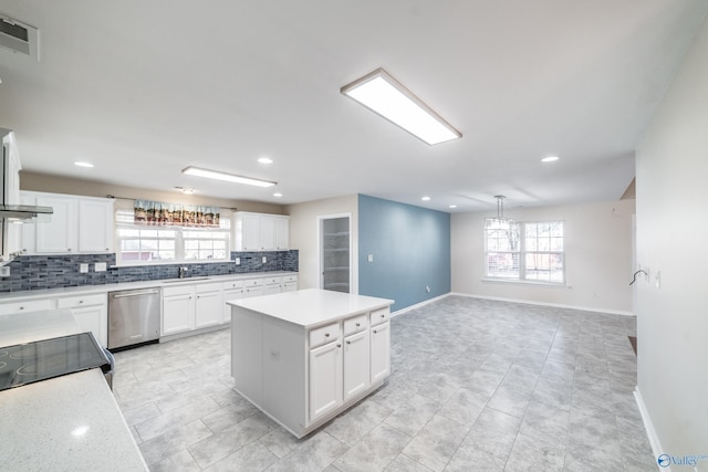 kitchen featuring stainless steel dishwasher, a healthy amount of sunlight, a kitchen island, and white cabinetry