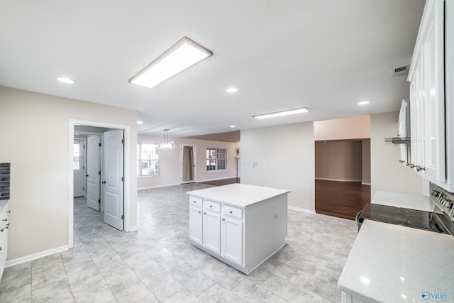 kitchen with a kitchen island, white cabinetry, and range with electric cooktop