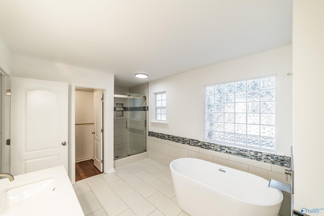 bathroom with tile patterned floors, vanity, plus walk in shower, and tile walls