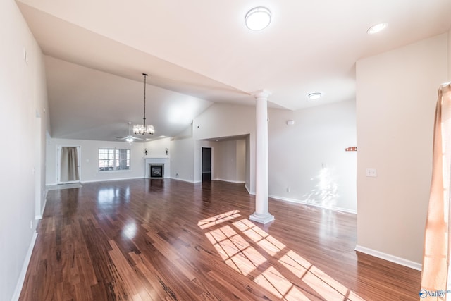 unfurnished living room with hardwood / wood-style floors, a chandelier, lofted ceiling, and ornate columns