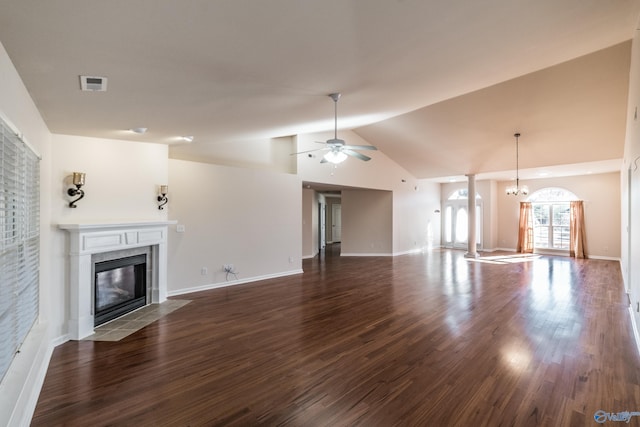 unfurnished living room featuring ceiling fan with notable chandelier, dark hardwood / wood-style flooring, a fireplace, and vaulted ceiling