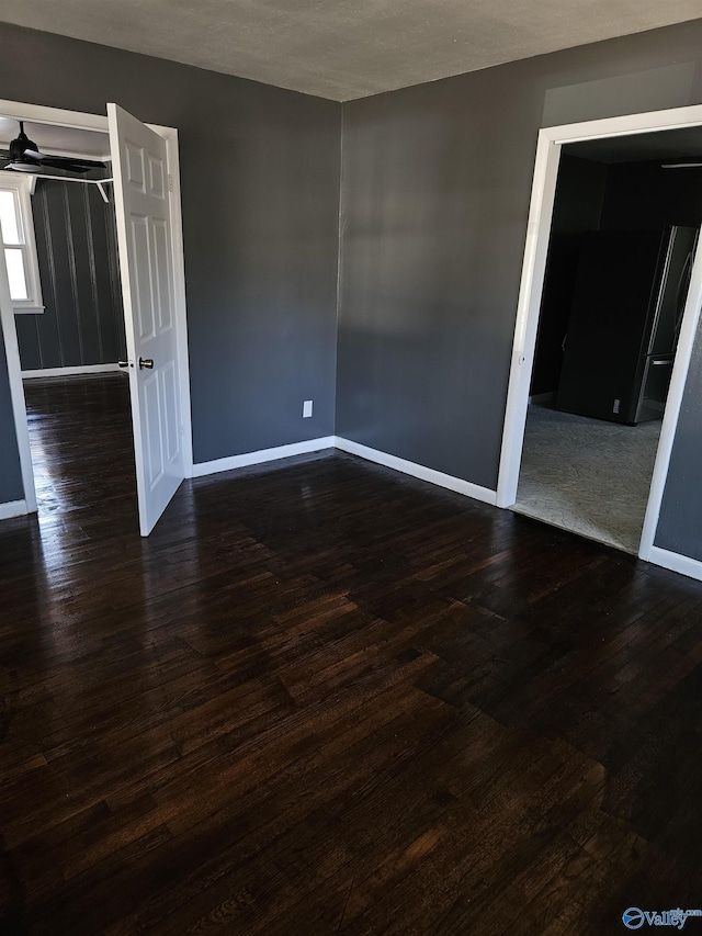 spare room with dark wood-type flooring and ceiling fan