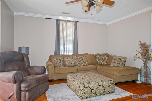 living room featuring a ceiling fan, visible vents, crown molding, and wood finished floors