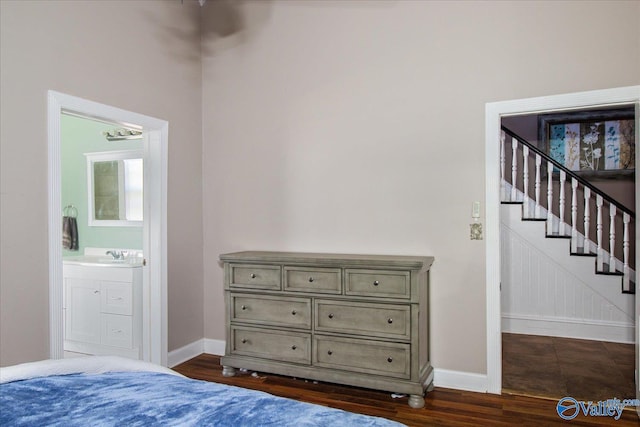 bedroom with dark wood-style flooring, a sink, ensuite bath, and baseboards