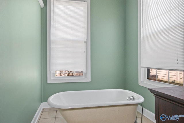 full bath featuring a freestanding tub, tile patterned flooring, and baseboards