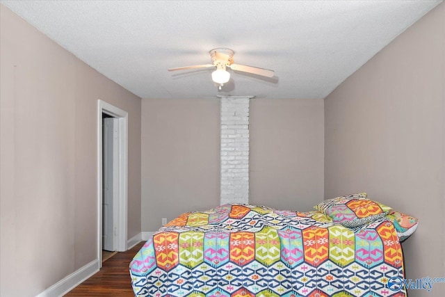 bedroom with a textured ceiling, ceiling fan, dark wood-type flooring, and baseboards