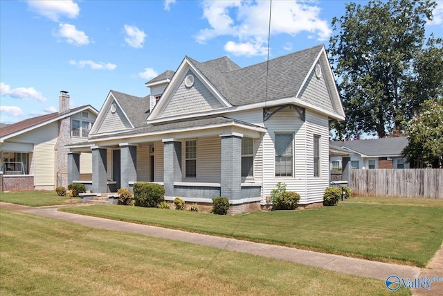 view of front of house featuring a front yard, covered porch, roof with shingles, and fence