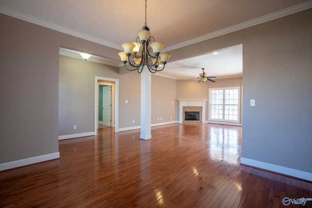 unfurnished living room featuring ceiling fan with notable chandelier, a fireplace, ornamental molding, and dark hardwood / wood-style floors