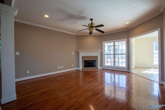 unfurnished living room with hardwood / wood-style flooring, a premium fireplace, ceiling fan, ornamental molding, and a textured ceiling