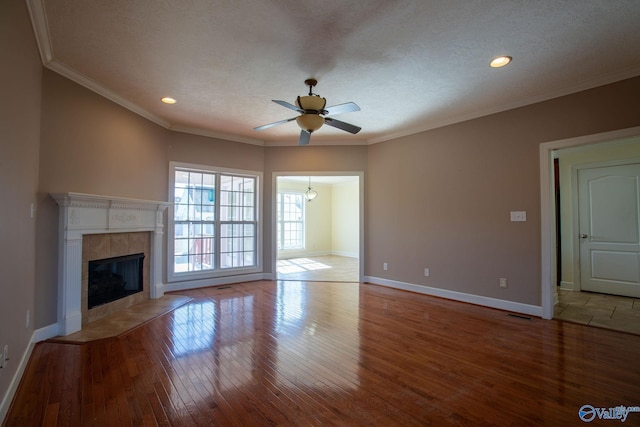 unfurnished living room featuring a tiled fireplace, ornamental molding, and light wood-type flooring