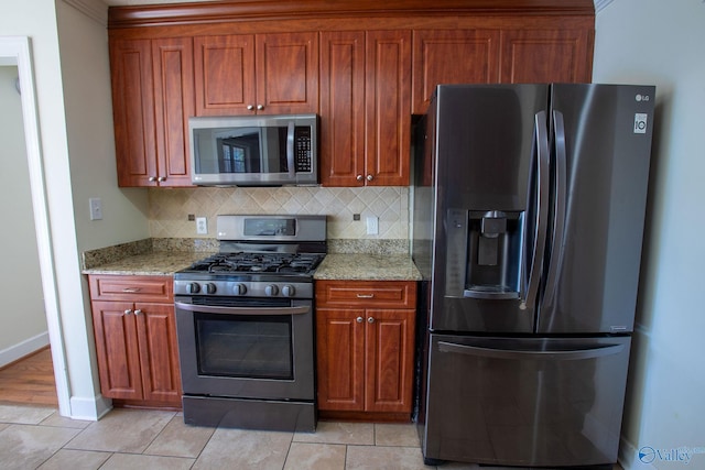 kitchen with light stone counters, stainless steel appliances, decorative backsplash, and light tile patterned floors