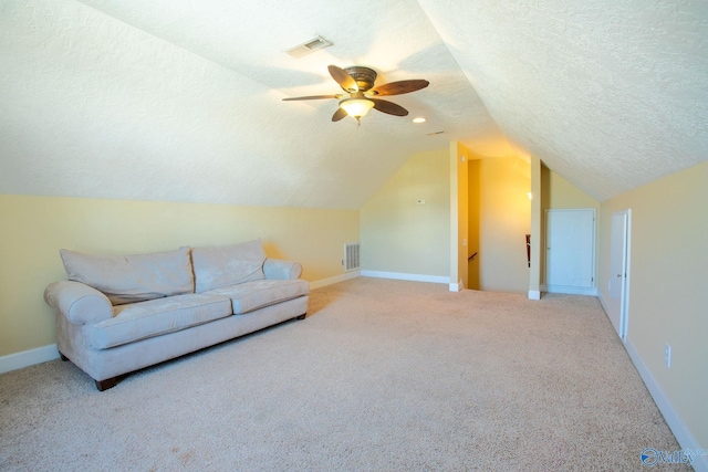 interior space with vaulted ceiling, carpet floors, ceiling fan, and a textured ceiling