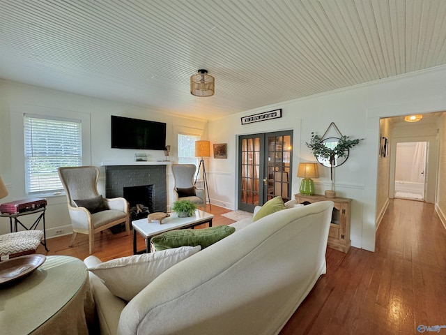 living area with a fireplace, wood finished floors, and french doors