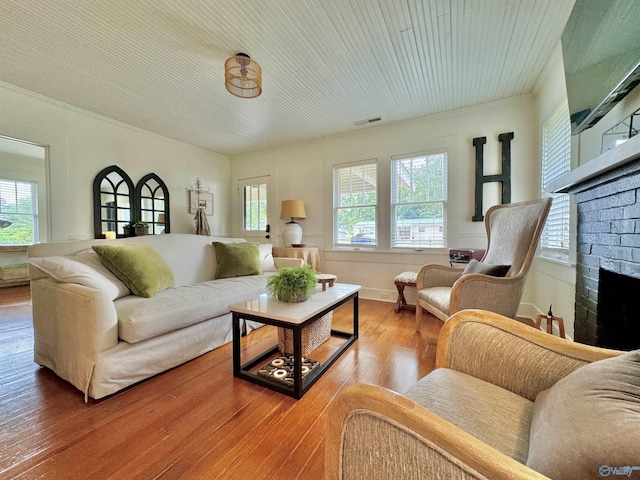 living area featuring a fireplace, wood finished floors, and visible vents