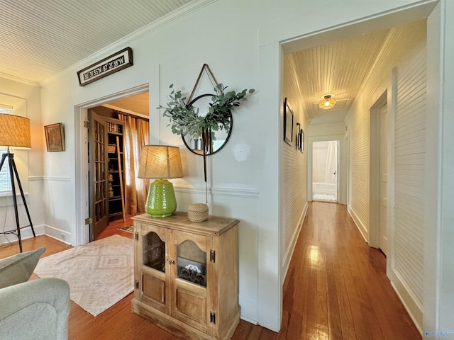 hallway with ornamental molding and hardwood / wood-style floors