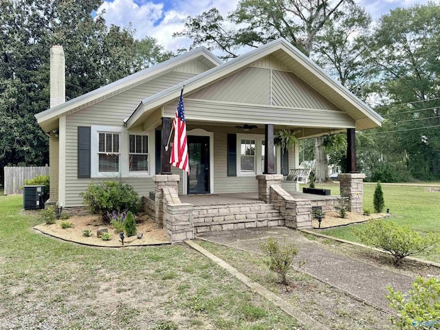 bungalow-style home featuring a chimney, central air condition unit, covered porch, a ceiling fan, and a front yard