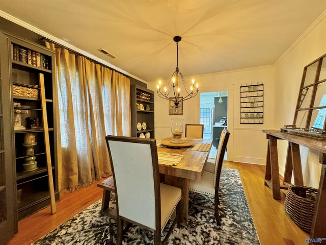 dining space featuring light wood-type flooring, crown molding, and a notable chandelier