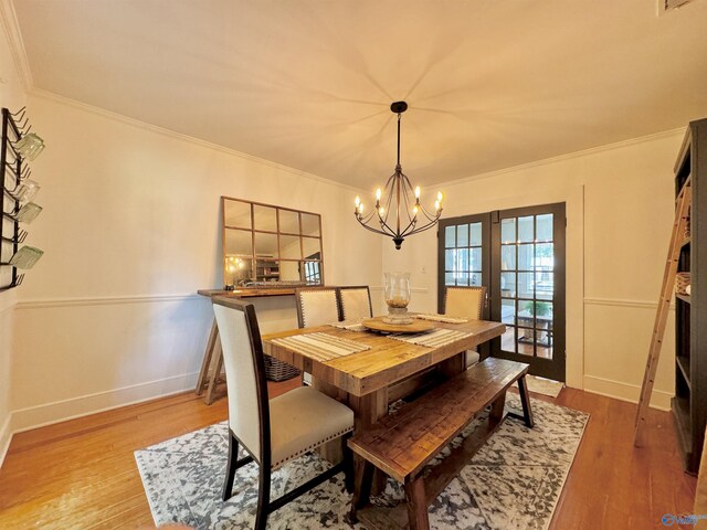 dining area featuring crown molding, wood-type flooring, french doors, and an inviting chandelier