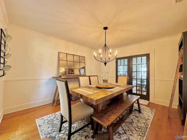 dining area featuring crown molding, an inviting chandelier, and wood finished floors