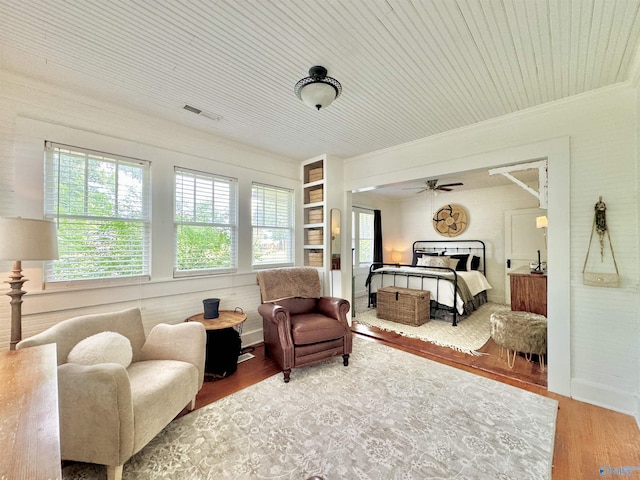 bedroom featuring multiple windows, crown molding, visible vents, and wood finished floors