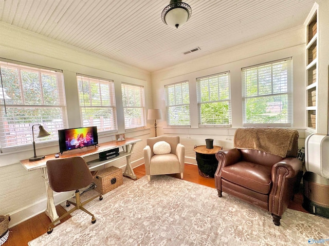 office with built in shelves, a healthy amount of sunlight, and wood-type flooring